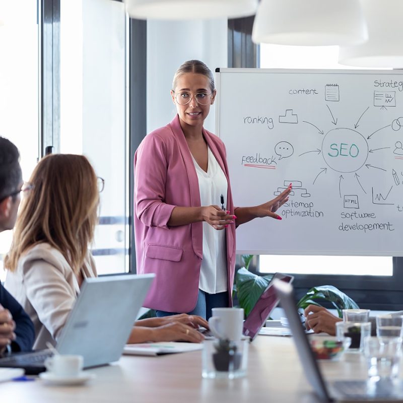 young-businesswoman-pointing-at-white-blackboard-a-NU2N2WV.jpg